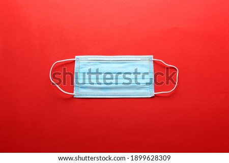 
Three-layer heat-sealed protection mask for clinical use for covid-19 pandemic on red background