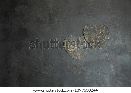 Two gold heart on dark textured background. Place for text