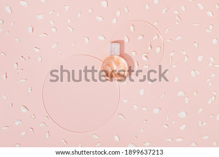Cosmetic product in transparent plastic bottle with glass circular disks, beautiful shadows on background set sail champange colred. Sunlight, top view.