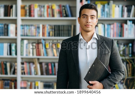 Portrait of hispanic man in formal wear at the workplace. Successful male manager looks at the camera, smiling. Influential businessman standing in modern office, show self confidence Royalty-Free Stock Photo #1899640456
