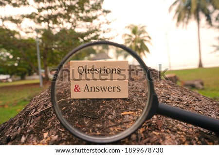 Conceptual image: Wooden blocks written Questions And Answers and magnifying glass at outdoor. Selective focus or Depth of field