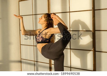 Young attractive woman practicing yoga,standing in Natarajasana exercise, Lord of the Dance pose, at home.Fitness and Yoga training concept.Healthy lifestyle,slow living.