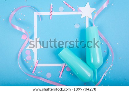 Party Holiday Background with ribbon, stars, birthday candles, gift box empty frame and confetti on blue background. Studio Photo