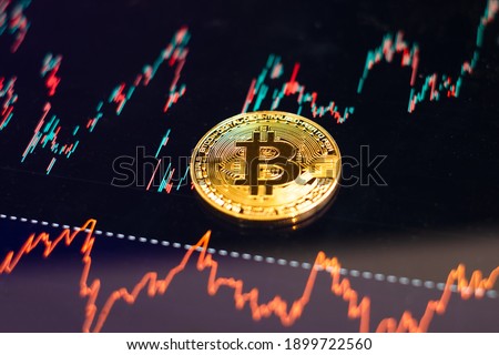 Bitcoin gold coin and defocused chart background. Virtual cryptocurrency concept.