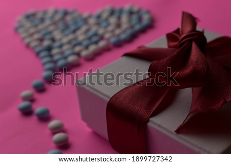 Heart shape candy chip and gift box on pink background