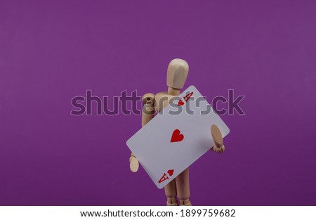 Wooden puppet mannequin holding ace of hearts on purple background.