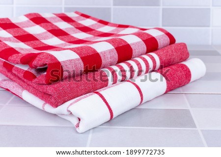 Folded red checkered picnic kitchen towels on a table