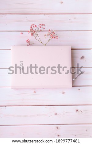 Diary pink organizer with cute pink dried flowers sign 2021 on white pink wooden background. 