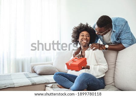 Valentine's day. Couple gives gift box to the Valentine's Day in the room. Couple at home. Hugging, kissing and enjoying spending time together while celebrating Saint Valentine's Day with gift box 