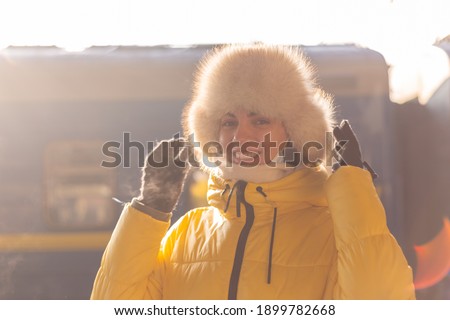 Young happy woman at the railway station near the train on a sunny winter day