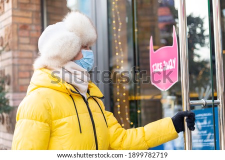 Happy young woman at the door of the restaurant on a cold winter day, lettering, takeaway food.