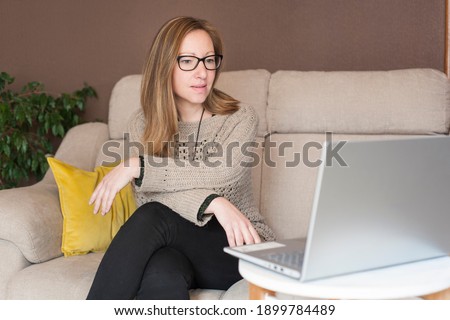 A woman works from home sitting on the sofa