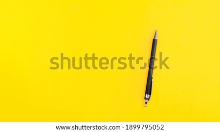 Black metal nib ballpoint pen on yellow background with copy space, text place. School education. Tool of author writer. Banner with automatic pencil. Stationery shop advertising. Simple business card