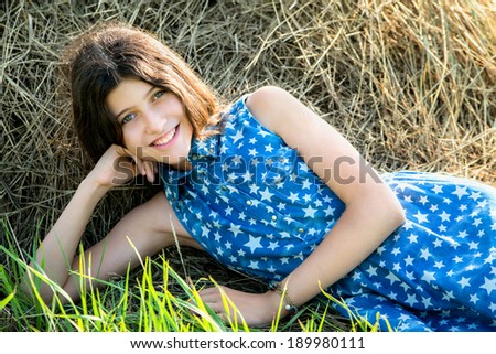 cute teen girl in blue dress sitting on the farm on hay background