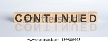 CONTINUED word from wooden blocks on white desk