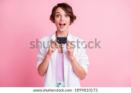 Photo of excited young woman dressed white shirt holding credit card arms hands open mouth isolated pink color background