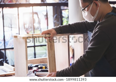 A carpenter measures the planks to assemble the parts, and build a wooden table for the customer