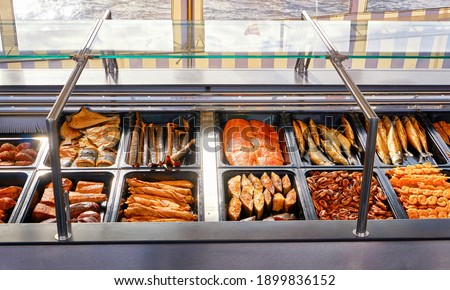 Smoked fish for sale on a boat in the harbor with Baltic Sea water in the background.