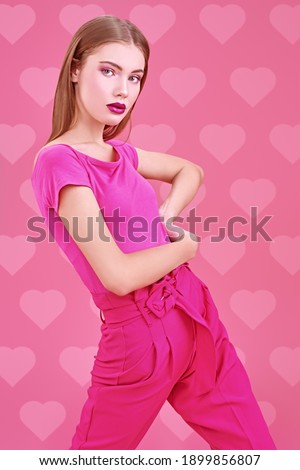 Beautiful girl fashion model poses at studio in trendy crimson suit on a pink background. Glamorous pink style.
