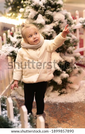 cute little blond baby girl admire Christmas tree and decoration full body photo