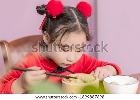Lovely little Chinese girl eating dumplings in New Year's clothes