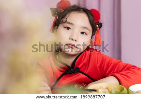 Lovely little Chinese girl eating dumplings in New Year's clothes