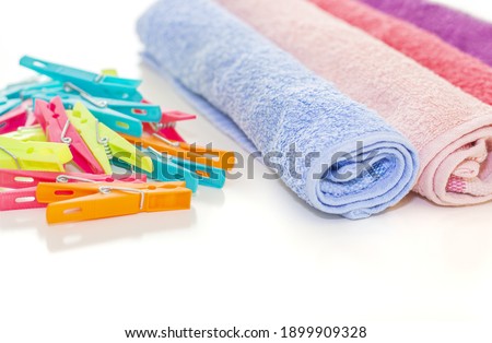 Colorful, clean and wrapped towels and many plastic clothespins on a white surface - laundry, cleaning
