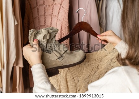 Woman shopper, customer choosing shoes, boots, clothes. Assortment of female clothing, footwear in garment store. Shopping.