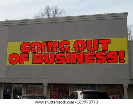 Going Out of Business.  A going out of business banner on a bankrupt storefront.  					