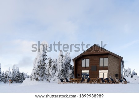Winter landscape. Wooden house on mountain and fir tree under the snow. High quality photo