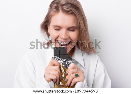 Close up portrait of young happy woman eating dark chocolate over white background