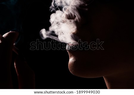 Fine art portrait of beautiful woman with cigarette on black background