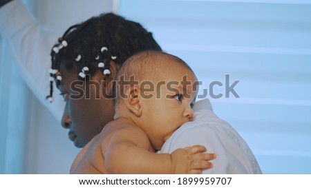 Happy multiracial family. Father holding his baby boy and looking through the window. High quality photo