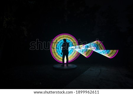 one person standing against beautiful blue and yellow circle light painting as the backdrop