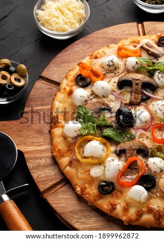 Pizza with mozzarella ,olives and mushroom. Italian cuisine. Ingredients for making pizza on a black background. Professional product photography. Top view.Concept for advertising restaurants.