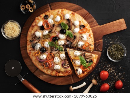 Pizza with mozzarella ,olives and mushroom. Italian cuisine. Ingredients for making pizza on a black background. Professional product photography. Top view.Concept for advertising restaurants.