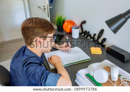 Left handed teenager doing homework on desk in his bedroom