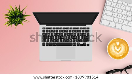 Laptop on table top view with a notebook, teacup, and green plant