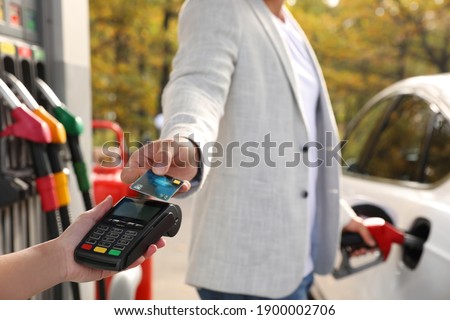 Man fills the car and paying with credit card at gas station, closeup
