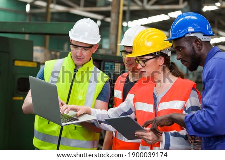 Diversity factory worker working with computer laptop in factory. Male and female worker wearing safety uniform, helmet and gloves at work factory. Group of worker working at factory Royalty-Free Stock Photo #1900039174