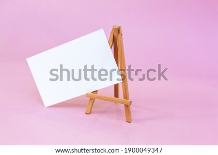 Wooden easel with white sheet. Vector illustration. Pink background.