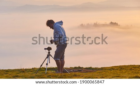 photographer watches the camera while shooting time lapse in the mountains