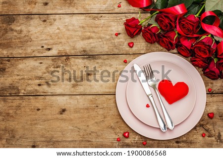 Romantic dinner table. Love concept for Valentine's or mother's day, wedding cutlery. Bouquet of fresh burgundy roses, vintage wooden boards background Royalty-Free Stock Photo #1900086568