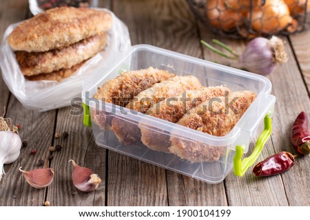 Frozen cutlets in a container. Ready frozen food. Fast cooking concept. Semi finished frozen cutlets Royalty-Free Stock Photo #1900104199