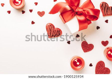 Love background: Valentines day red hearts, romantic gift box, candle on white table. Romantic message template with copy space. Flat lay, top view, copy space