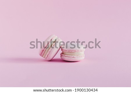 Pink pastel macarons on a pink pastel background. Place for text.