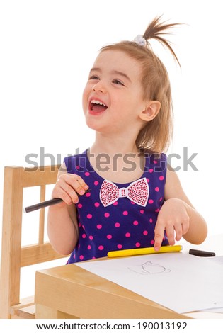 Happy little girl with crayons at the table