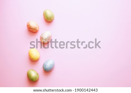 Easter greeting card: colorful golden shiny eggs over pink background