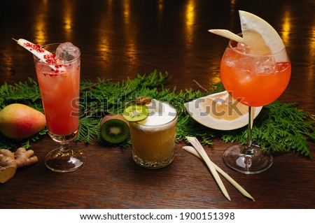 Three exotic cocktails on the table. Sour cocktail, pear cocktail and aperol spritz