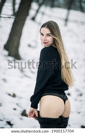 beautiful girl takes off her pants in winter in the park